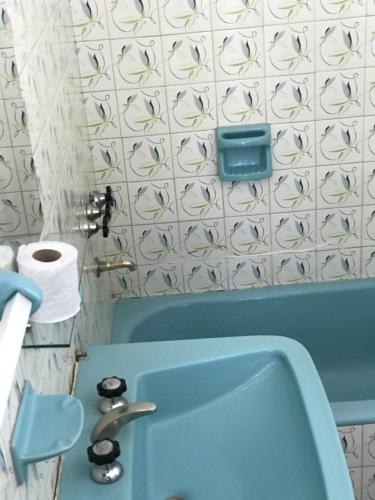 a bathroom with a blue sink and a white tiled wall at Hotel Ro Che Hil Tandil in Tandil