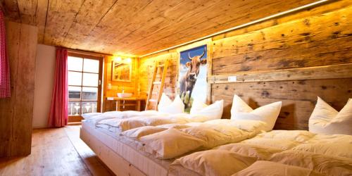 a bedroom with four beds in a room with a wooden wall at Haus Bergfelder in Hirschegg