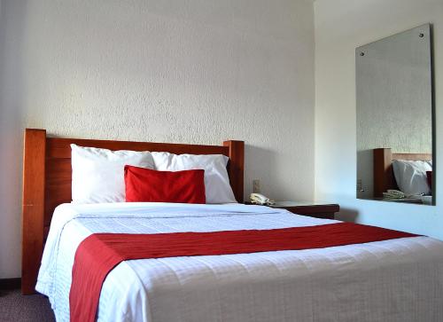 a bedroom with a large bed with a red pillow at Hotel Campestre Inn in León
