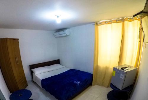 a small bedroom with a bed and a yellow curtain at Posada Cultural Bahia Sonora in San Andrés