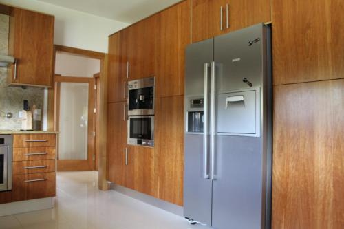 a stainless steel refrigerator in a kitchen with wooden cabinets at Casa de Coyra in Paredes de Coura
