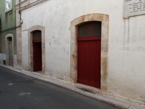 two red doors on the side of a white building at Appartamento in palazzina storica / Oberdan Suites in Alberobello