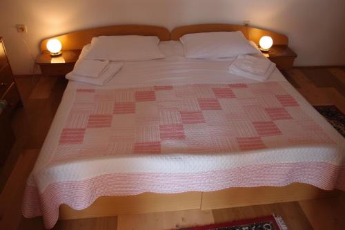 Una cama con un edredón rosa y blanco. en Villa Lina, en Ičići