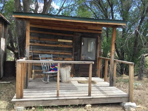 Cabaña con silla en una terraza de madera en Taos Goji Farm & Eco-Lodge Retreat, en Arroyo Seco