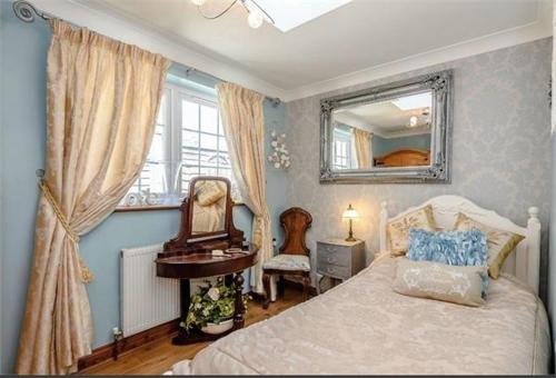 a bedroom with a bed and a mirror and a chair at Little Croft in Haddenham