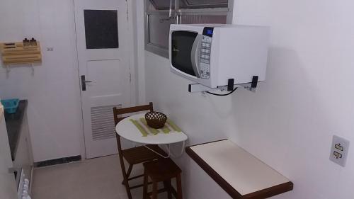 uma cozinha com uma mesa e um micro-ondas na parede em Apto 1 dorm. Guarujá - Pitangueiras - perto da praia no Guarujá