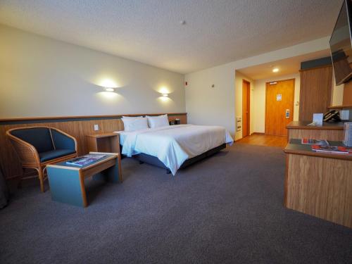 um quarto de hotel com uma cama grande e uma cadeira em Swiss-Belresort Coronet Peak em Queenstown