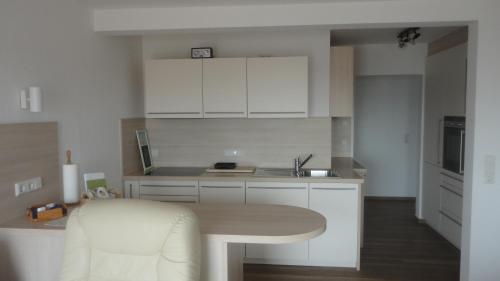 uma cozinha com armários brancos e uma mesa de cozinha em Ferienwohnung Ol Komede Wai 12c em Helgoland