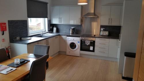 a kitchen with white cabinets and a table and a washer at Newtown Apartments in Boʼness