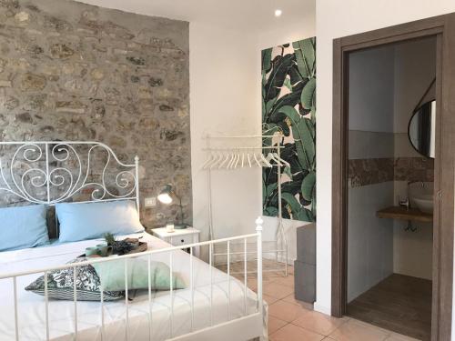 サロにあるCasa Castelloの白いベッドと石の壁が備わるベッドルーム1室