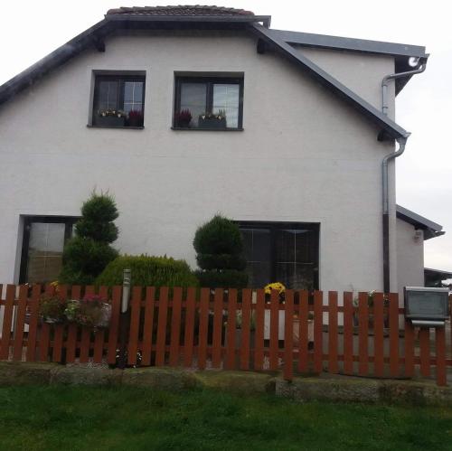 a white house with two windows and a wooden fence at Pension Family Club in Libišany