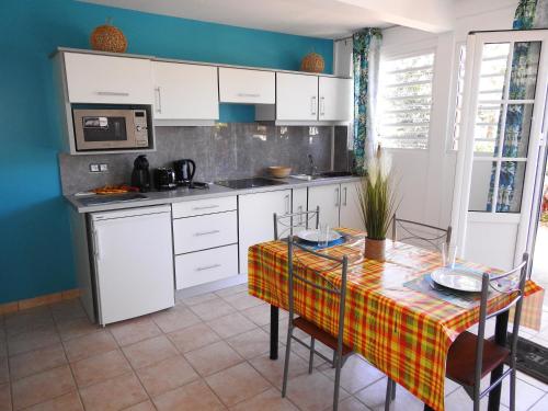 a kitchen with white cabinets and a table with chairs at gîte CITRONNELLE in Bouillante