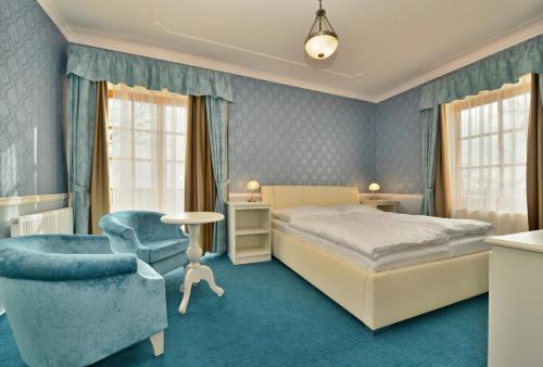 ein Hotelzimmer mit einem Bett und einem Stuhl in der Unterkunft Hotel Gold Chotoviny in Chotoviny