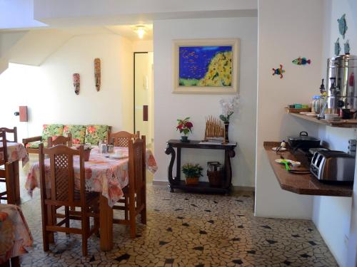 
a kitchen with a table, chairs, and a table cloth at Pousada Omnimare in Ubatuba
