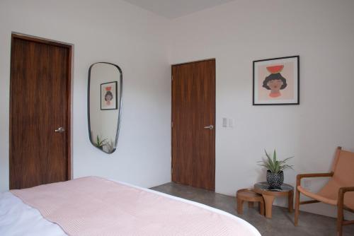 a bedroom with a bed and a mirror and a chair at Residencia Tropical Don Bonito in Sayulita