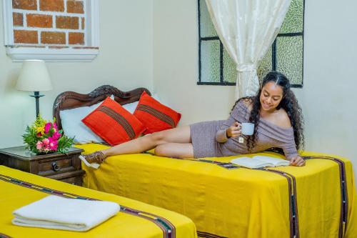 a woman laying on a bed reading a book at Posada San Vicente by AHS in Antigua Guatemala