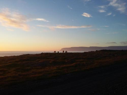 a group of people standing on a hill near the ocean at Hænuvík Cottages in Örlygshöfn