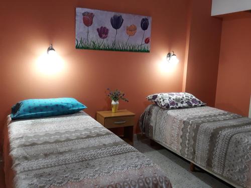 a bedroom with two beds and a painting on the wall at Departamento Luiggi con cochera in Bahía Blanca