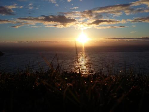 a sunset over the ocean with the sun in the sky at Hænuvík Cottages in Örlygshöfn