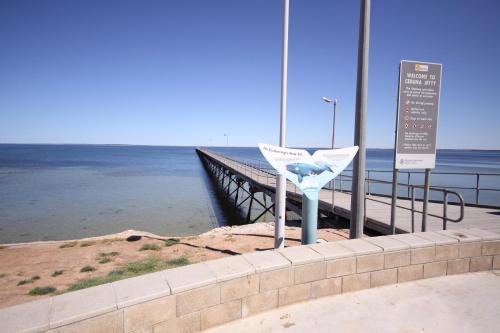 a pier with a sign next to the water at Ceduna Foreshore Caravan Park in Ceduna