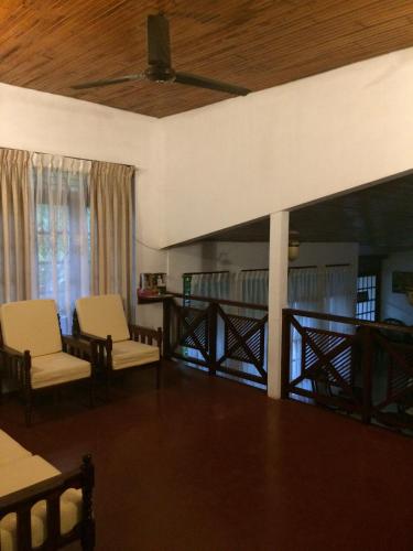 a living room with two chairs and a wooden ceiling at Galle Rest Home in Galle