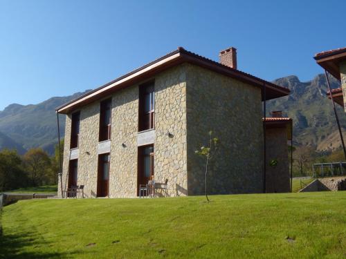 a large brick building with a grass field in front of it at La QuintaEsencia in La Pereda de Llanes