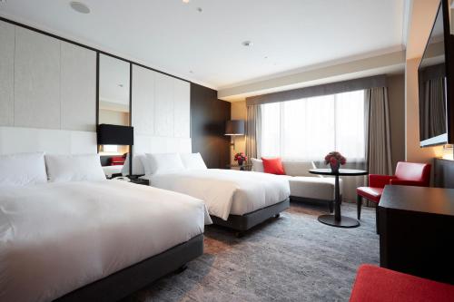a hotel room with two beds and a couch at Nagoya Tokyu Hotel in Nagoya
