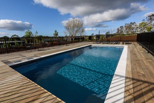 a swimming pool on a deck with a fence at Plume Villas in Matakana