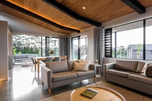 a living room with two couches and a table at Plume Villas in Matakana