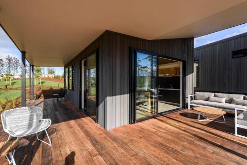 a house with a deck with a couch and chairs at Plume Villas in Matakana