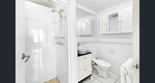 a white bathroom with a shower and a toilet at Shandelle Apartments in Alexandra Headland