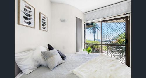 a bedroom with a bed and a large window at Shandelle Apartments in Alexandra Headland