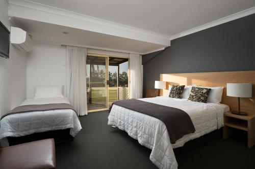 a hotel room with two beds and a window at Harkham Lodge in Pokolbin