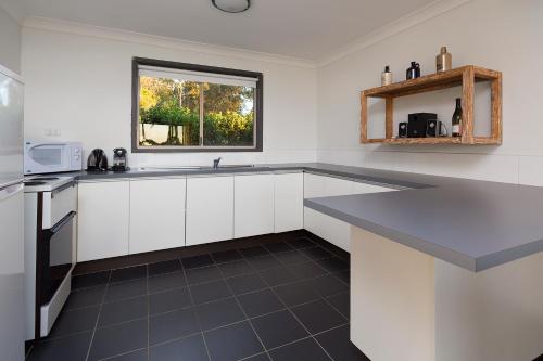 a kitchen with white cabinets and a blue counter top at Harkham Lodge in Pokolbin