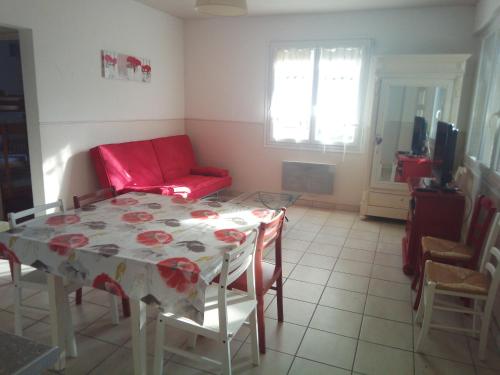 uma sala de estar com uma mesa e um sofá vermelho em Maison du Port em Narbonne Plage