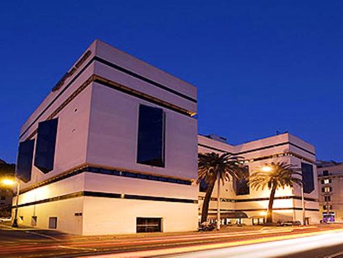 a building with palm trees in front of a street at Mercure Roma Centro Colosseo in Rome