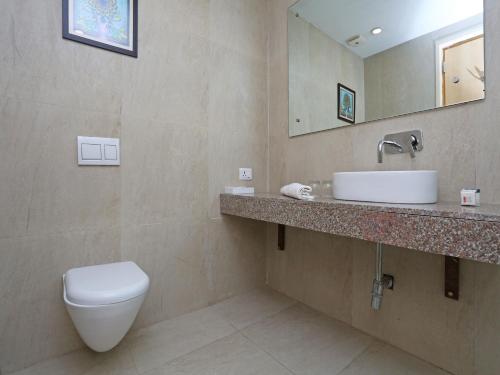 a bathroom with a toilet and a sink and a mirror at Four Leaf Service Suites, Haridwar in Roorkee