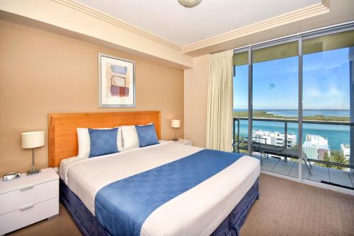 a bedroom with a bed and a large window at Pumicestone Blue in Caloundra