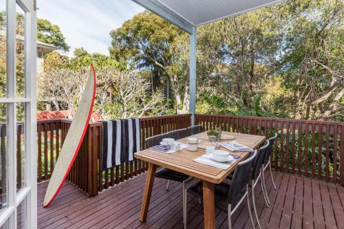 a wooden deck with a table and surfboards on it at Jetty House in Coffs Harbour