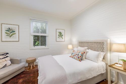 a white bedroom with a bed and a window at Jetty House in Coffs Harbour