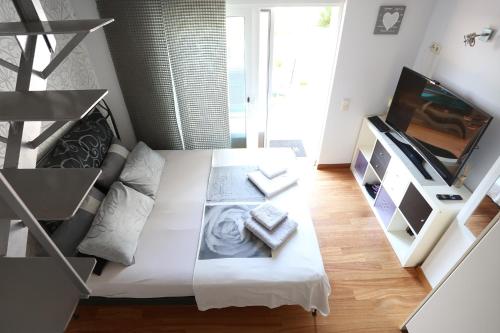 a small living room with a white couch and a tv at Thimari Sports & Spa with private pool and jacuzzi in Sounio