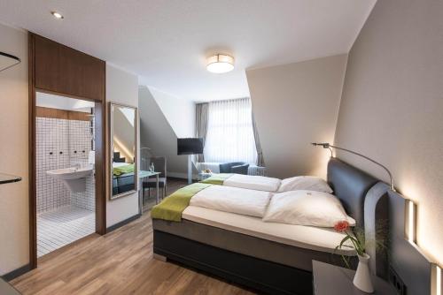 a bedroom with a large bed and a bathroom at Hotel am Markt in Fürstenau