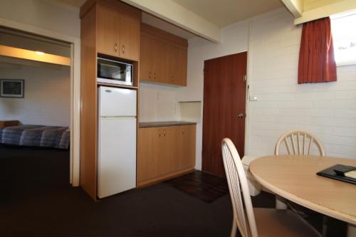 a kitchen with a table and a white refrigerator at Cobram Colonial Motor Inn in Cobram