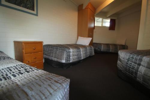 a hotel room with three beds and a dresser at Cobram Colonial Motor Inn in Cobram