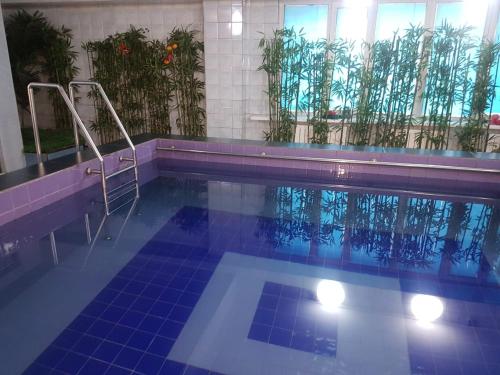 una piscina con suelo de baldosa azul en Hotel Kezdesu en Almaty