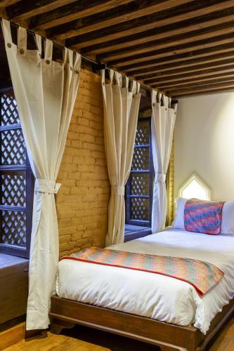 a bedroom with a bed with curtains and a window at Hotel Patan House in Pātan