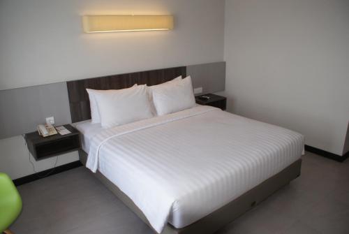 a bedroom with a large bed with white sheets and pillows at Swiss-Belhotel Borneo Samarinda in Samarinda