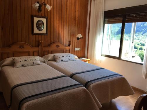 two beds in a hotel room with a window at Hotel Bellavista Ordesa in Torla