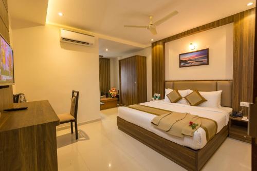 a hotel room with a large bed and a desk at Grand Plaza Suites in Kozhikode