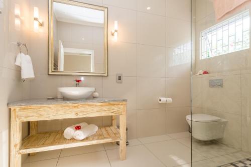 a bathroom with a sink and a toilet and a mirror at Beau Vallon Villa Chalets in Beau Vallon